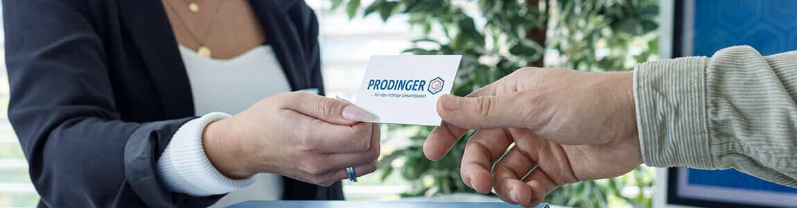 Mitarbeiterin von PRODINGER übergibt eine Karte mit Kontakt-Informationen