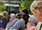 Während einer Ferienbetreuung machen kleine Kinder eine Ausfahrt auf dem Anhänger eines Traktors.
