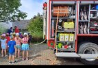 Kindergarten stehen am Hands-On Aktionstag von PRODINGER hilft neben einem Feuerwehrauto und schauen bei einer Löschübung zu.