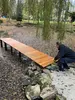 Ein Mitarbeiter von PRODINGER befestigt das letzte Holzmodul an dem Steg des Teiches.