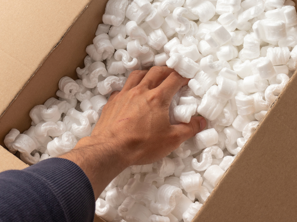 Hand verteilt weiße Verpackungschips in einem Karton